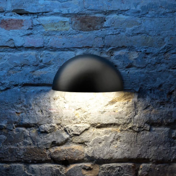 Lumenlight Bolero GII Midi 11 W sort (AO 6243700158) tændt på rustik blågrå murstensfacade med nedadrettet varmt lys